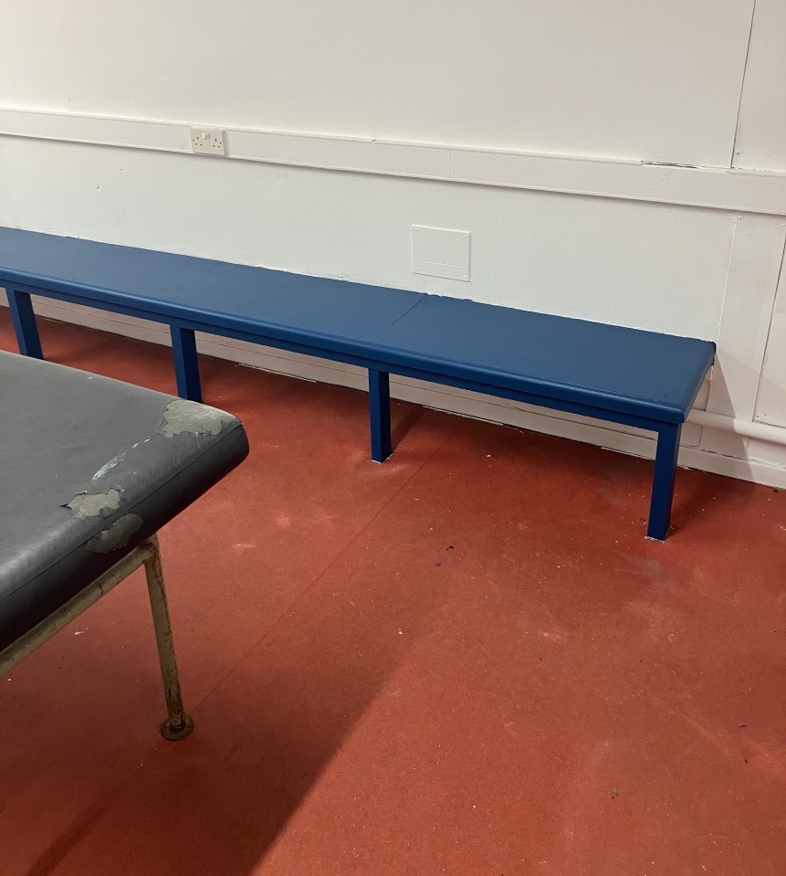 Blue bench in a room with red floor.