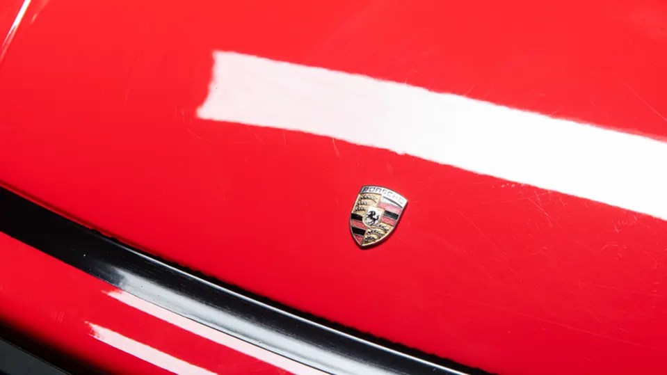 Porsche crest on a red Porsche 911 Junior children's car.