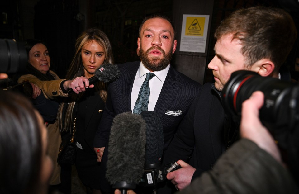 Conor McGregor leaving court surrounded by reporters.