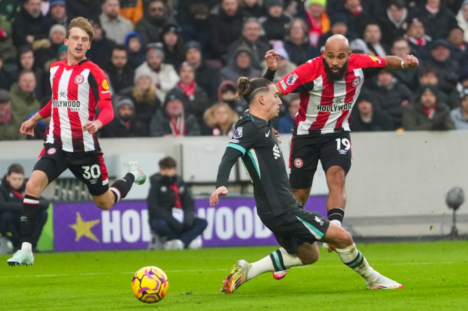 Brentford's Bryan Mbeumo takes a shot as Liverpool's Kostas Tsimikas, center, tries to close him down during the English Premier League soccer match between Brentford and Liverpool at the GTech Community Stadium in London, Saturday, Jan. 18, 2025. (AP Photo/Kirsty Wigglesworth)