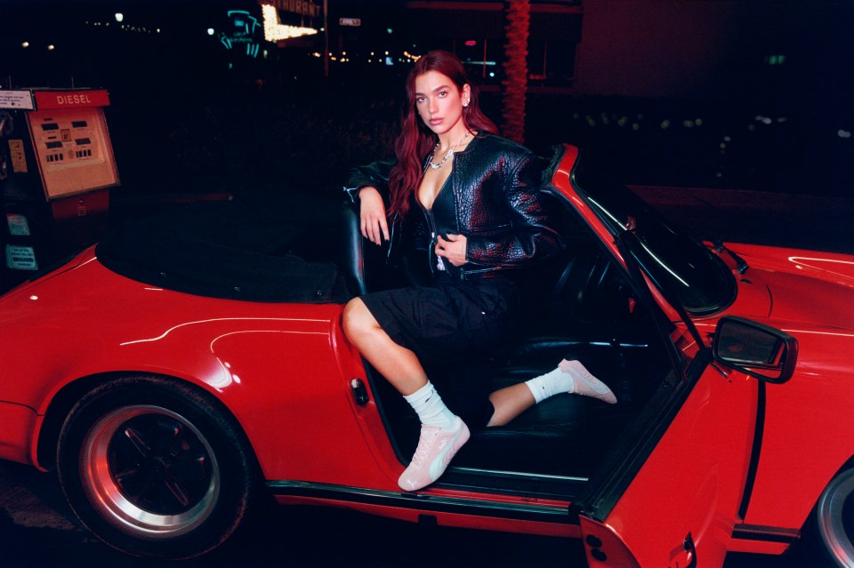 Dua Lipa in a red car.