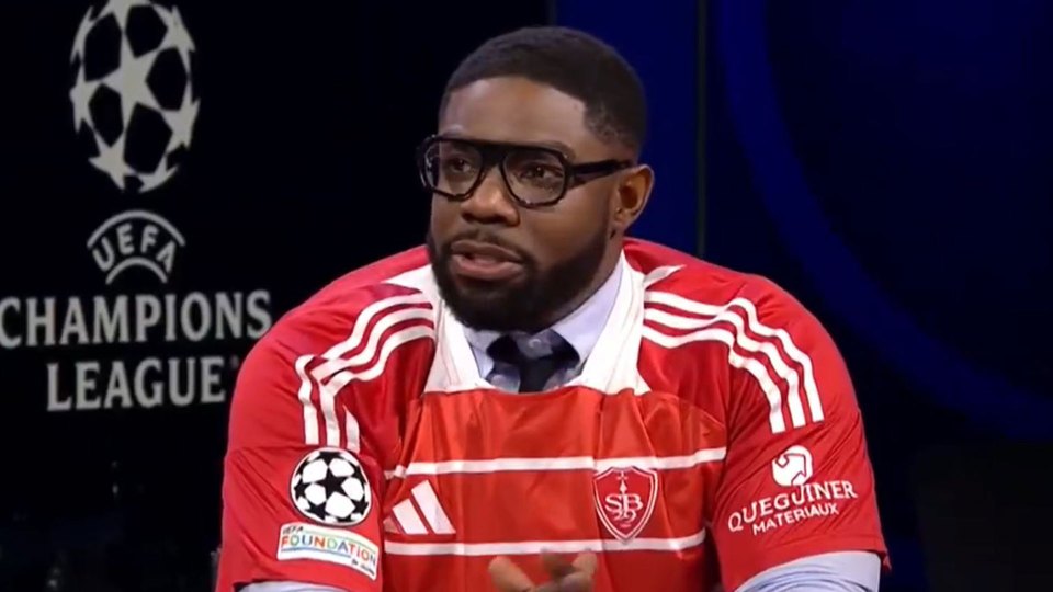 Man in a red soccer jersey speaking.