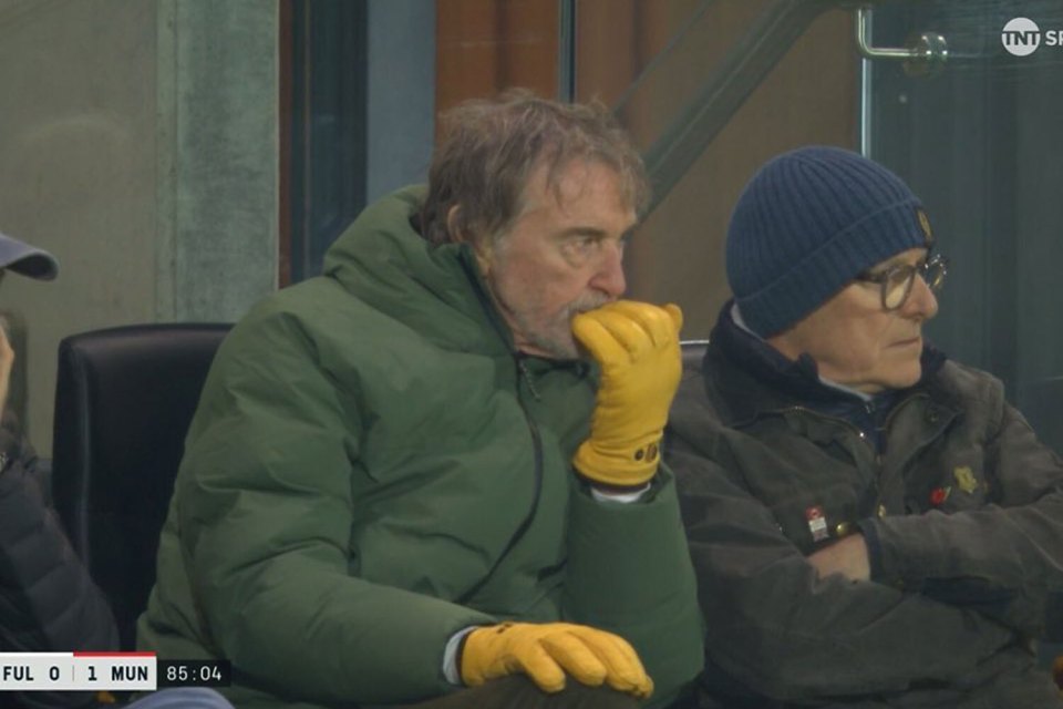 Two men wearing gloves watch a sporting event.