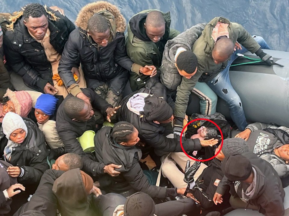 Spain’s sea search and rescue agency, shows a newborn baby (R) in the midst of migrants on board an inflatable boat