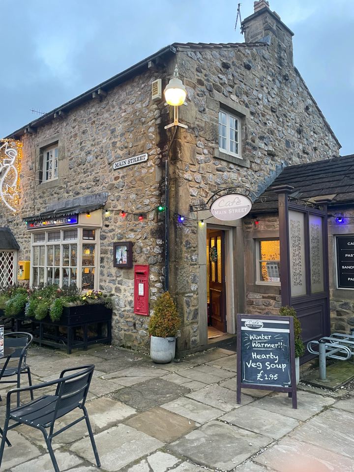 Stone building with cafe sign and outdoor seating.