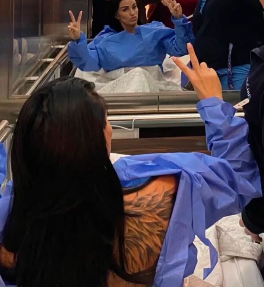 Woman in hospital gown showing off tattoo and making peace sign.