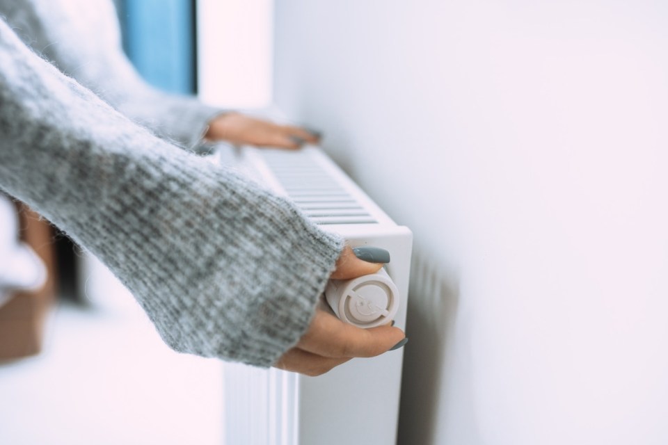 Person adjusting a radiator thermostat.