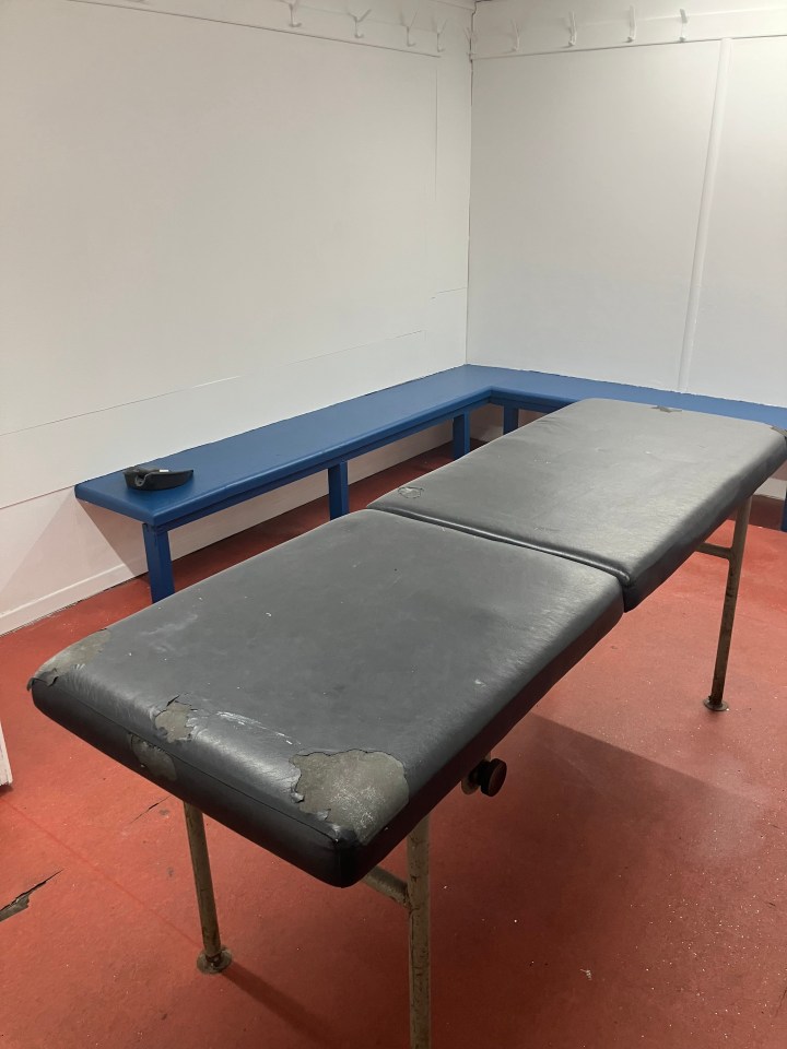 Worn massage table and bench in a room.