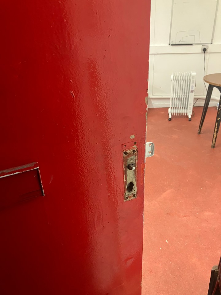 A red door with a damaged lock.