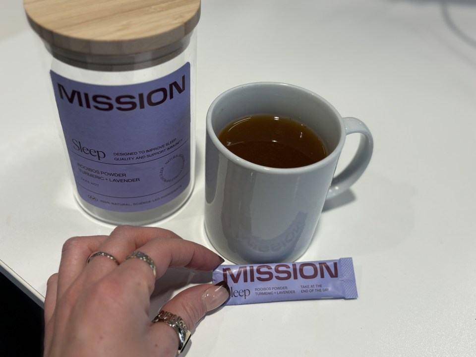 A mug of tea, a jar of Mission Sleep powder, and a single-serving packet of the same powder.