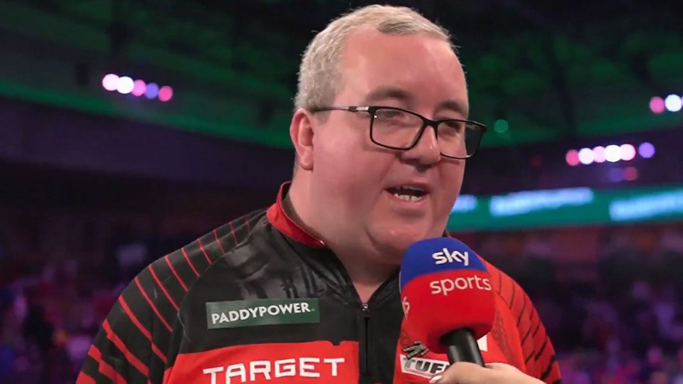 A man in glasses and a red and black shirt is being interviewed.