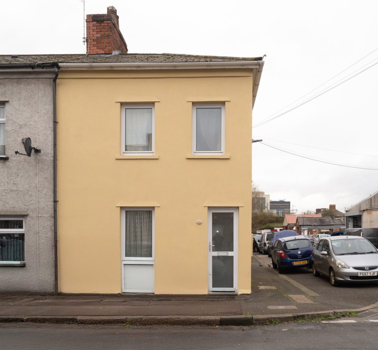 A pale yellow two-story house for sale.