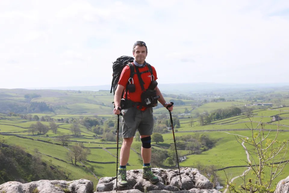 Hiker standing on a rock overlooking a valley in Yorkshire.