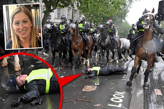 Police officer lying on the ground after falling from a horse during a protest.