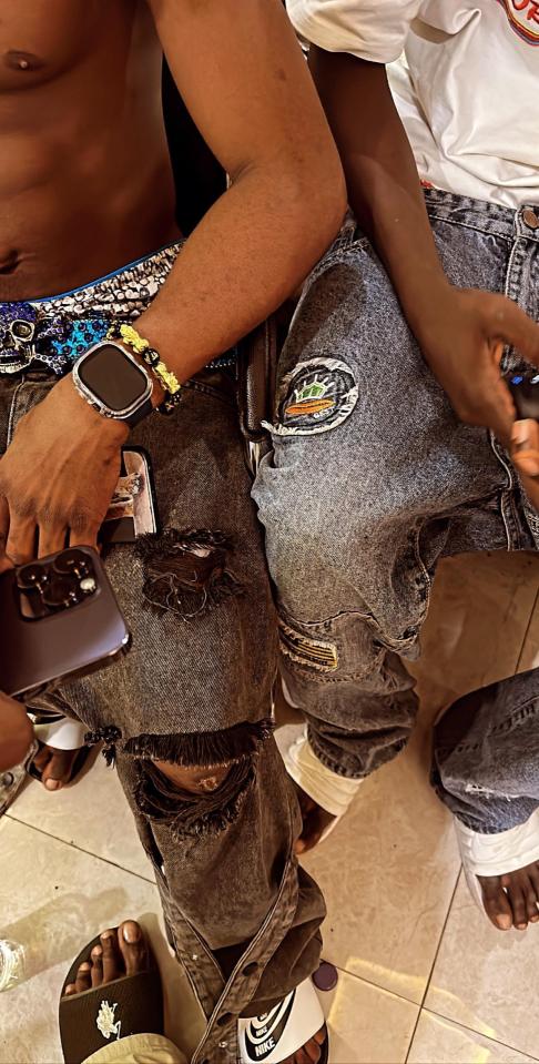 Close-up of two people wearing ripped jeans and sandals.