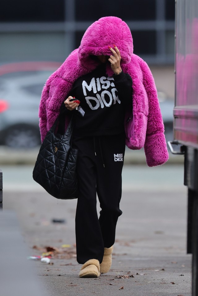 Person wearing a pink fluffy hooded jacket and black Miss Dior sweatpants.