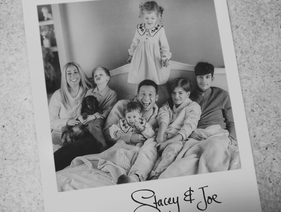 Black and white photo of a family with their dog on a bed.