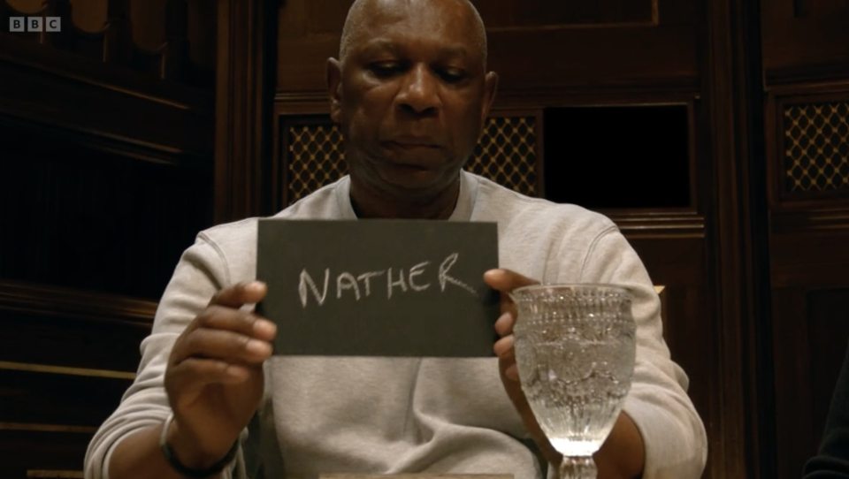 A man holds a card that says "NATHER".