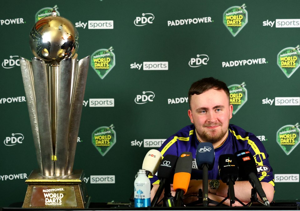 Luke Littler at a press conference with the PDC World Darts Championship trophy.