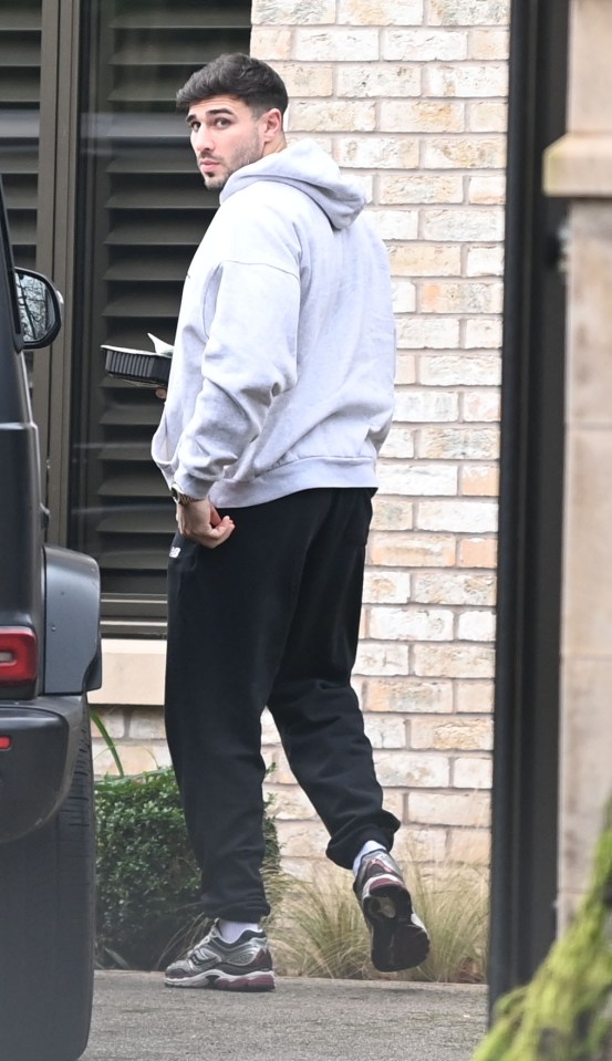 Man carrying takeout container walks away from a house.