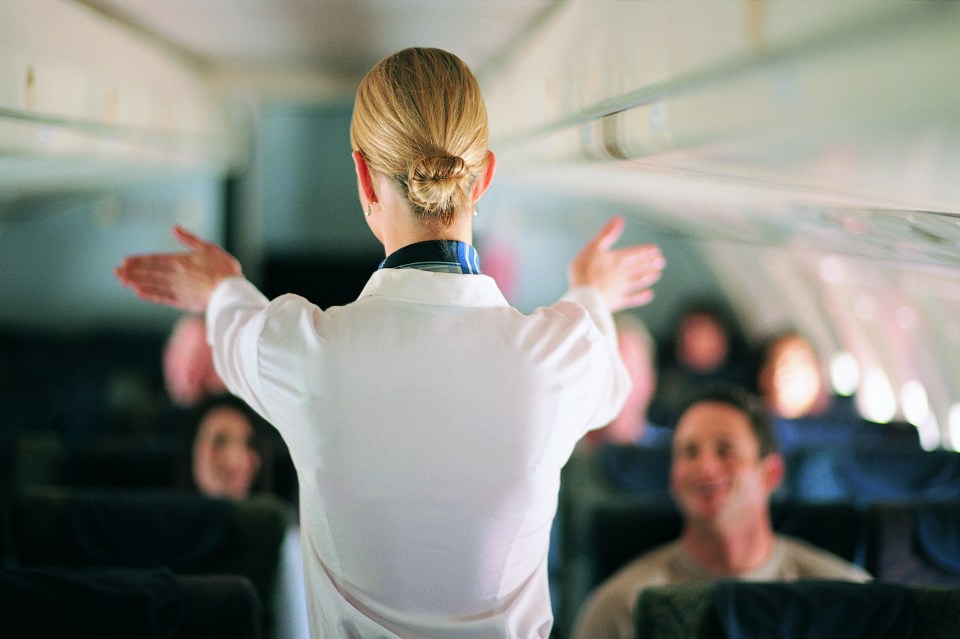 Flight attendant demonstrating safety procedures to passengers.