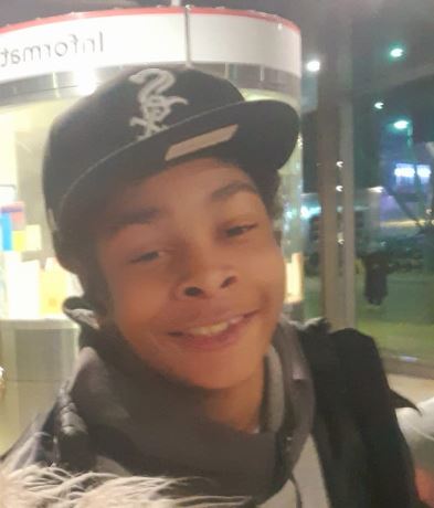 Close-up photo of a smiling young person wearing a baseball cap.