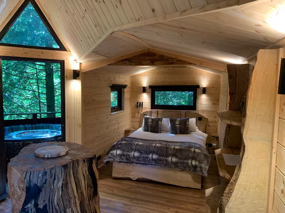 Treetop bedroom with a bed, hot tub, and wood accents.