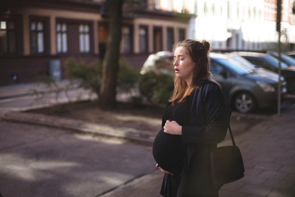 Pregnant woman standing on a city street.