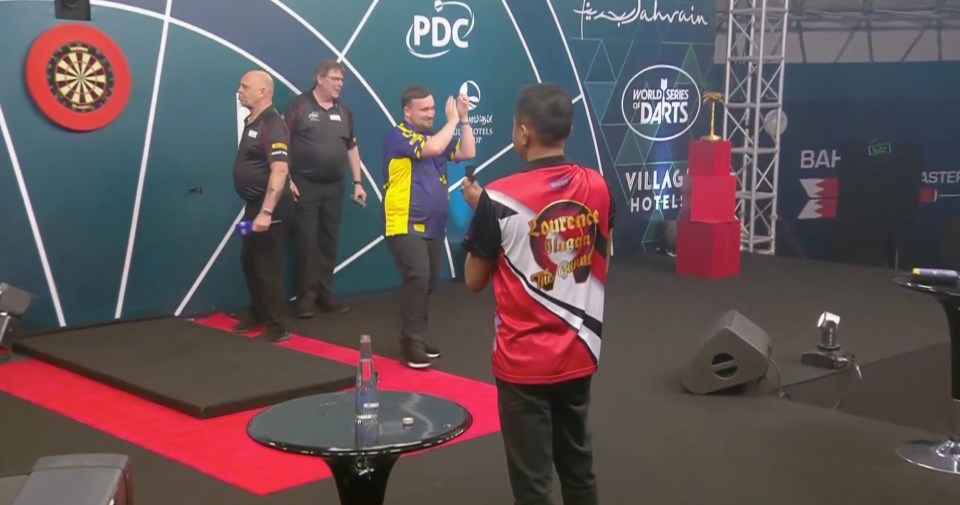 Darts players on stage at a tournament.