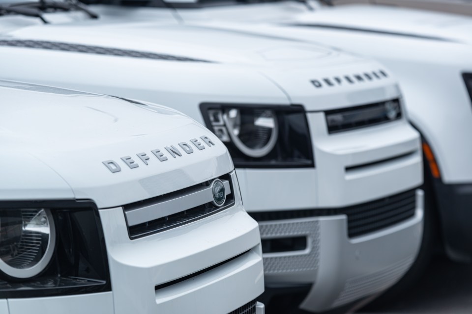 Close-up of three white Land Rover Defenders.