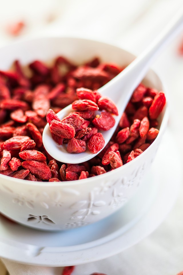 Goji berries in a white bowl with a spoon.