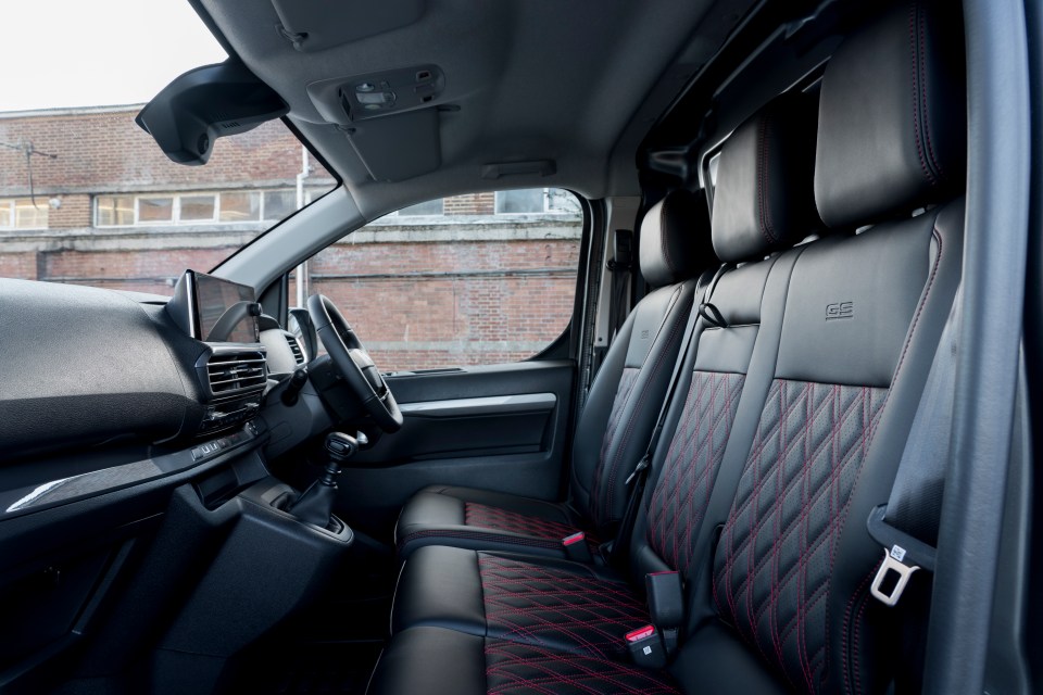 Interior view of a van with black leather seats and red stitching.