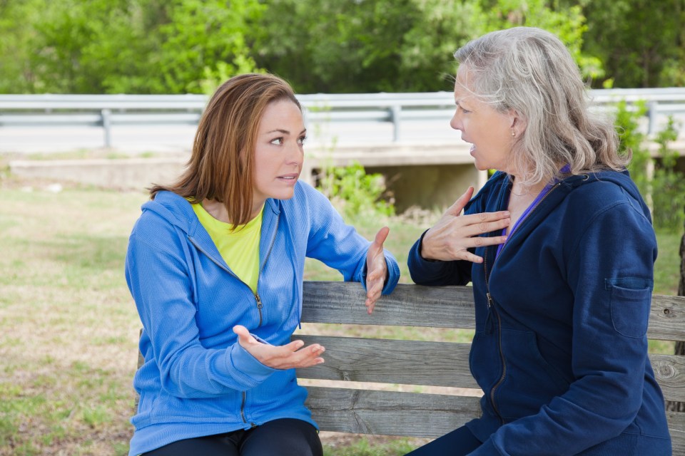 Two women having a serious conversation on a park bench.