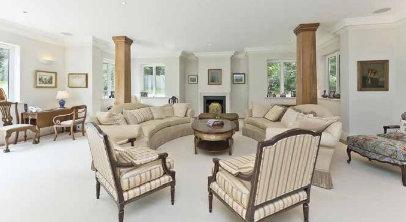 Large living room with beige sofas and armchairs arranged around a coffee table.