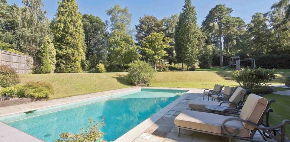 Swimming pool and lounge chairs in a backyard.