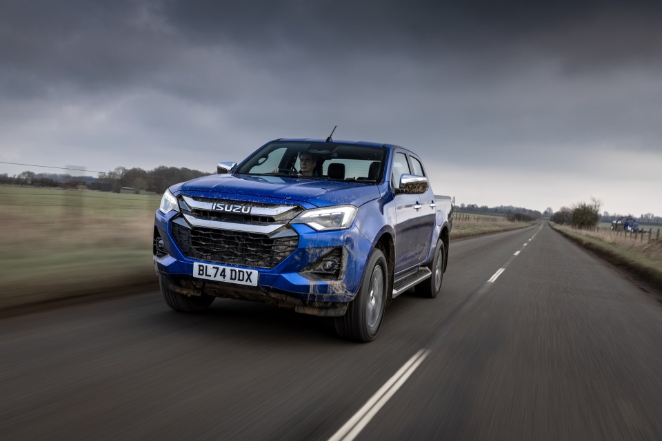 Blue Isuzu pickup truck driving on a road.