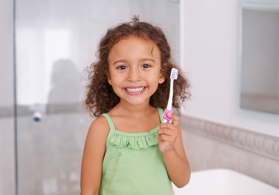 Smiling girl holding toothbrush.