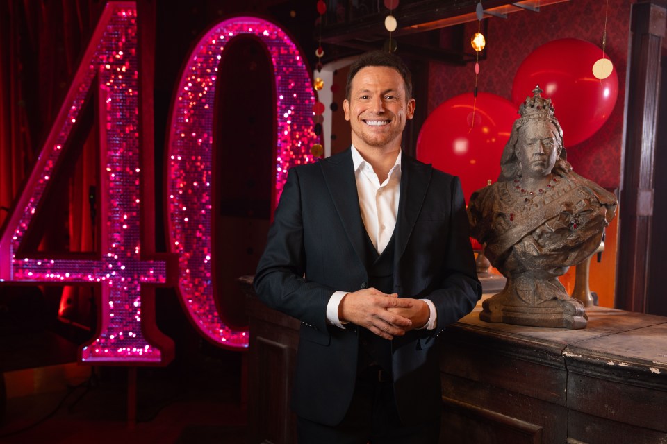 Man in suit standing in front of a large, sparkling number 40 and a bust.