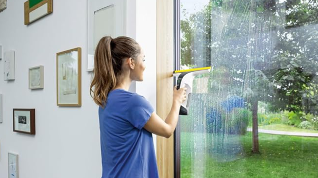 Woman cleaning a window with an electric window cleaner.