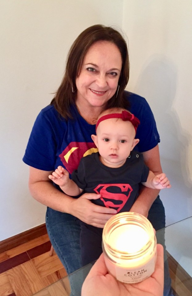 Woman holding baby wearing Superman shirts.