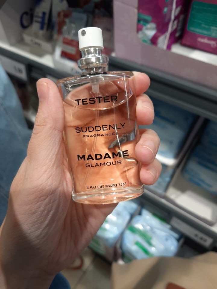 Hand holding a tester bottle of "Suddenly Madame Glamour" Eau de Parfum.