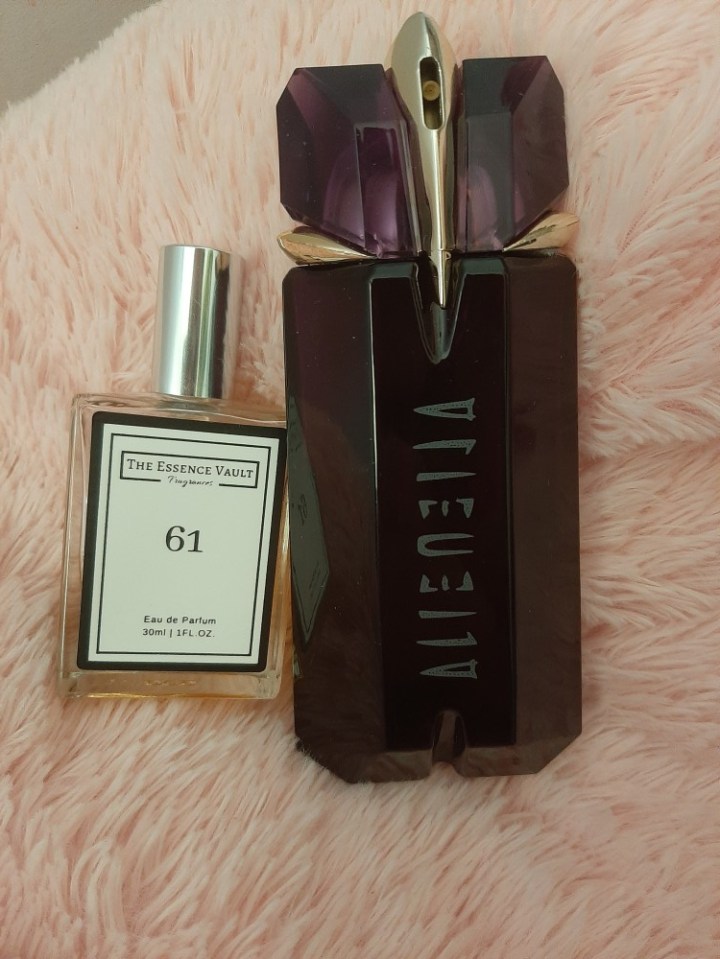 A smaller bottle of The Essence Vault perfume next to a larger bottle of Alien perfume.