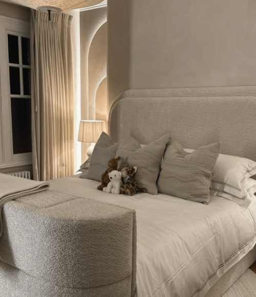 Beige bedroom with plush bed, stuffed animals, and neutral decor.