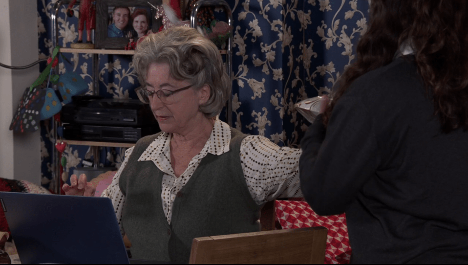 Older woman using a laptop, another woman standing behind her.