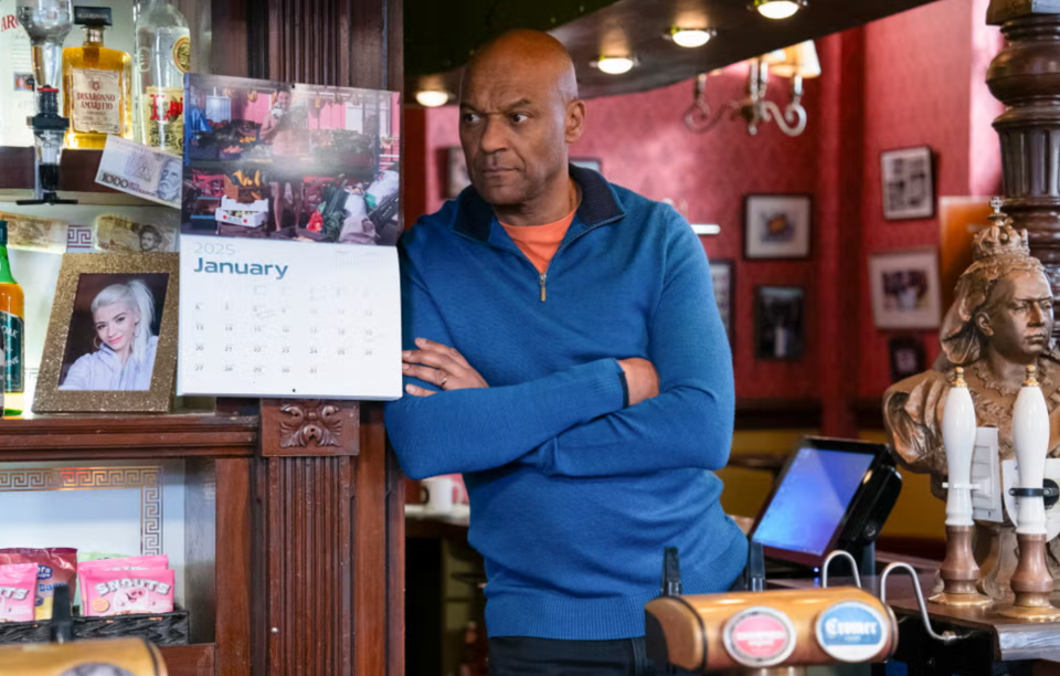 Man standing in a pub with a 2025 January calendar visible.