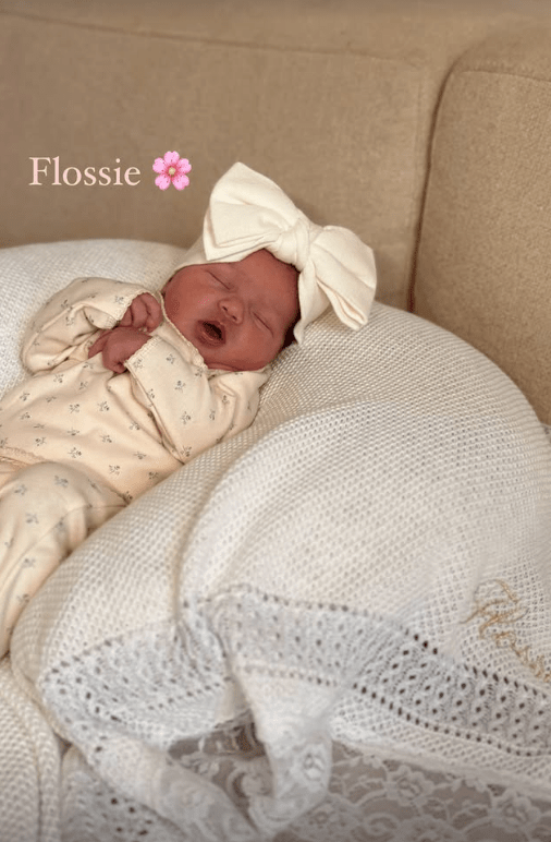 Newborn baby Flossie sleeping on a white blanket.