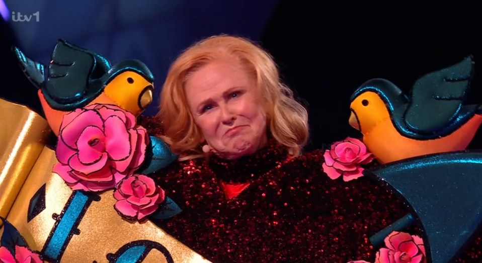 A woman in a sparkly red costume adorned with birds and roses.