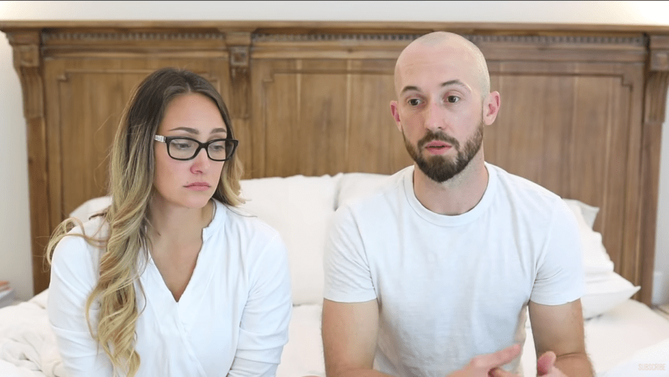 Couple sitting on a bed, talking.