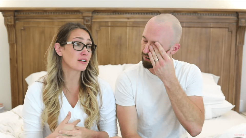 Upset couple sitting on a bed.