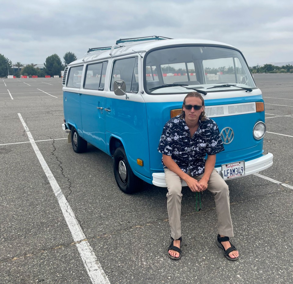 Man sitting in front of his blue VW van.